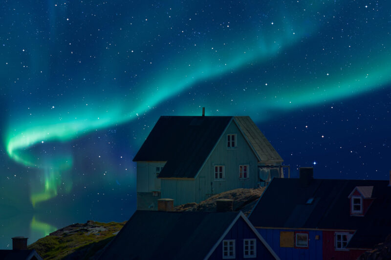 northern lights behind a colourful house in Greenland